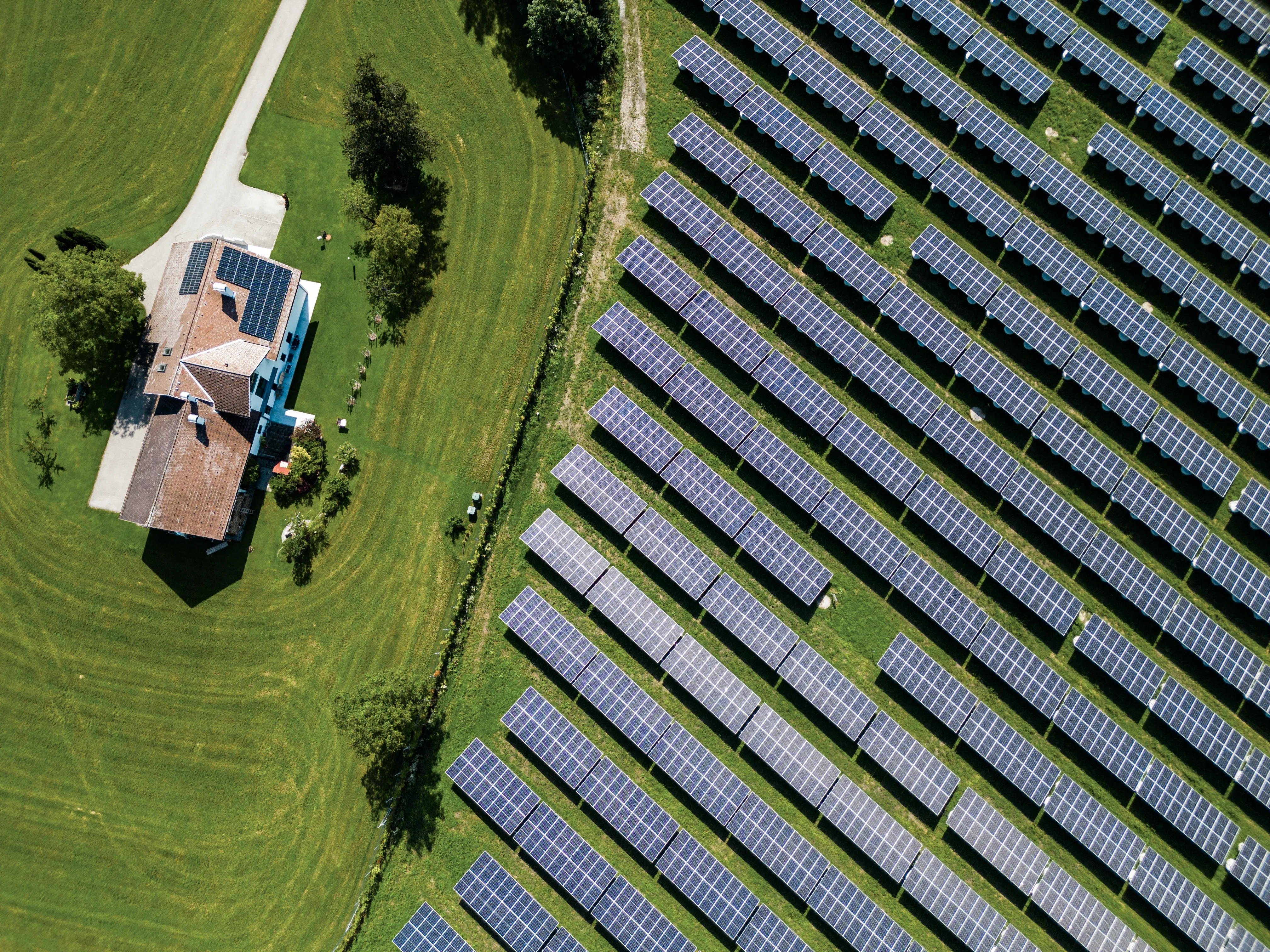 Grüne Landschaft, ein Einfamilienhaus und eine Photovoltaik-Anlage aus der Vogelperspektive.