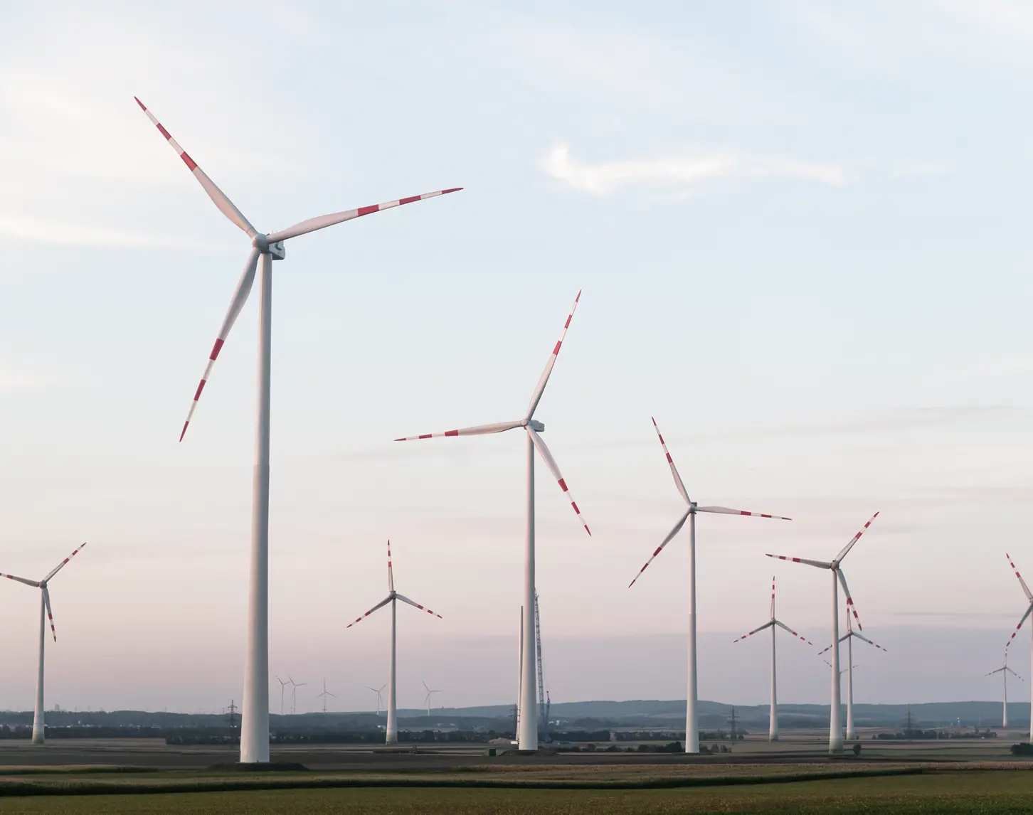 Das Bild zeigt einen kleineren Windpark in der Abenddämmerung.