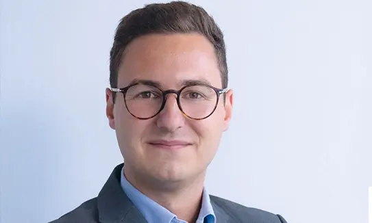 Lukas Assmair, Head of Procurement bei NÖM AG lächelt in die Kamera.