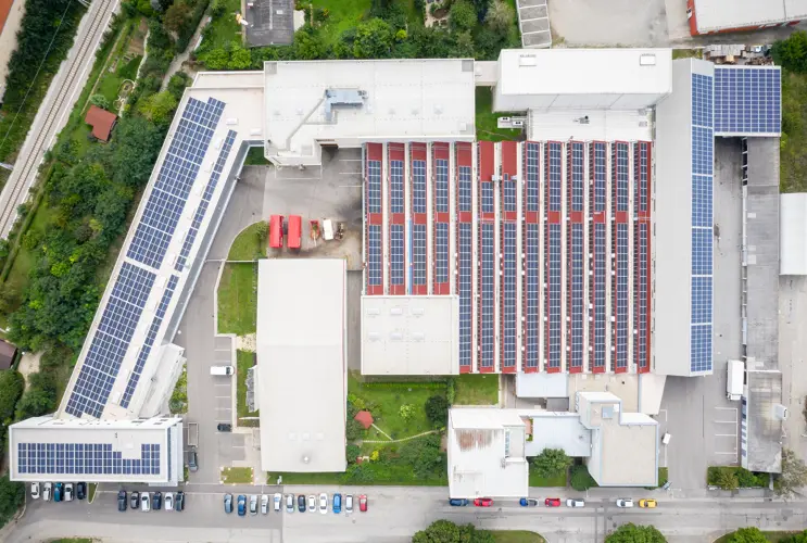 Wir sehen eine Industriephotovoltaikanalage auf dem Dach eines Unternehmens von oben.