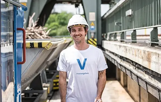 VERBUND-Mitarbeiter Robert Schießl aus dem Kraftwerk Rosenheim trägt auf diesem Foto einen Helm und ein weißes T-Shirt mit einem blauem V drauf.